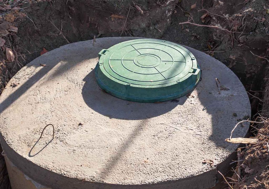 A concrete septic tank with green manhole.