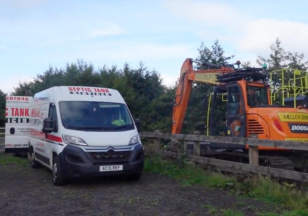 A van and a digger installing a new tank.