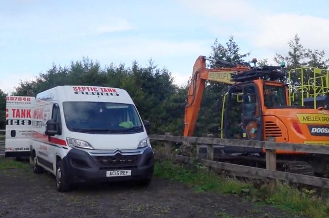 A van and a digger installing a new tank.