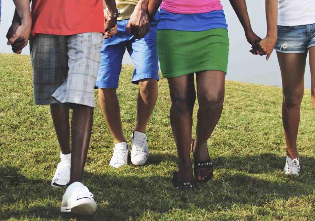 A group of people holding hands on grass.