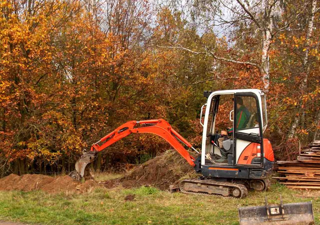 A mini excavator preparing the ground for a septic tank installation.