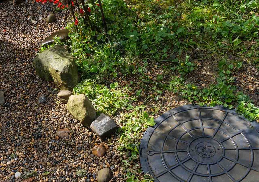 A septic tank cover near gravel.