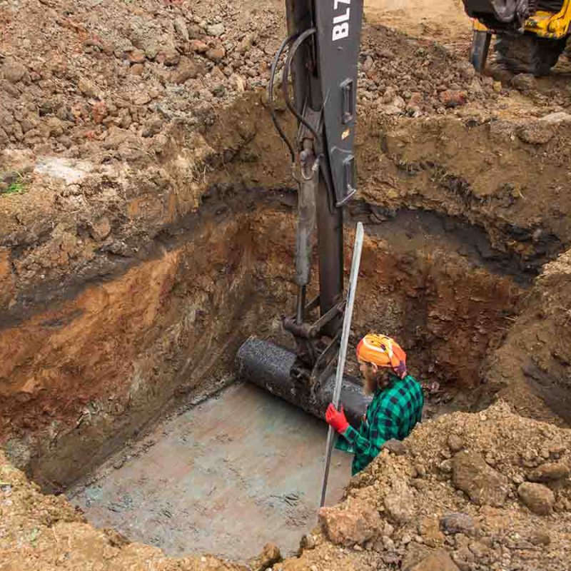 A man digging a big hole for a septic tank.