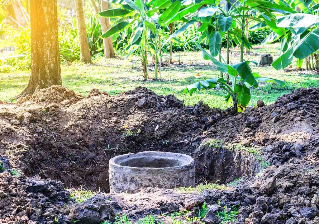 A concrete septic tank in a hole in the ground.