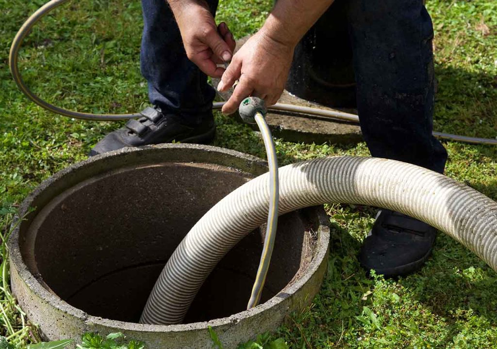 A worker examines waste being sucked from a cesspit.