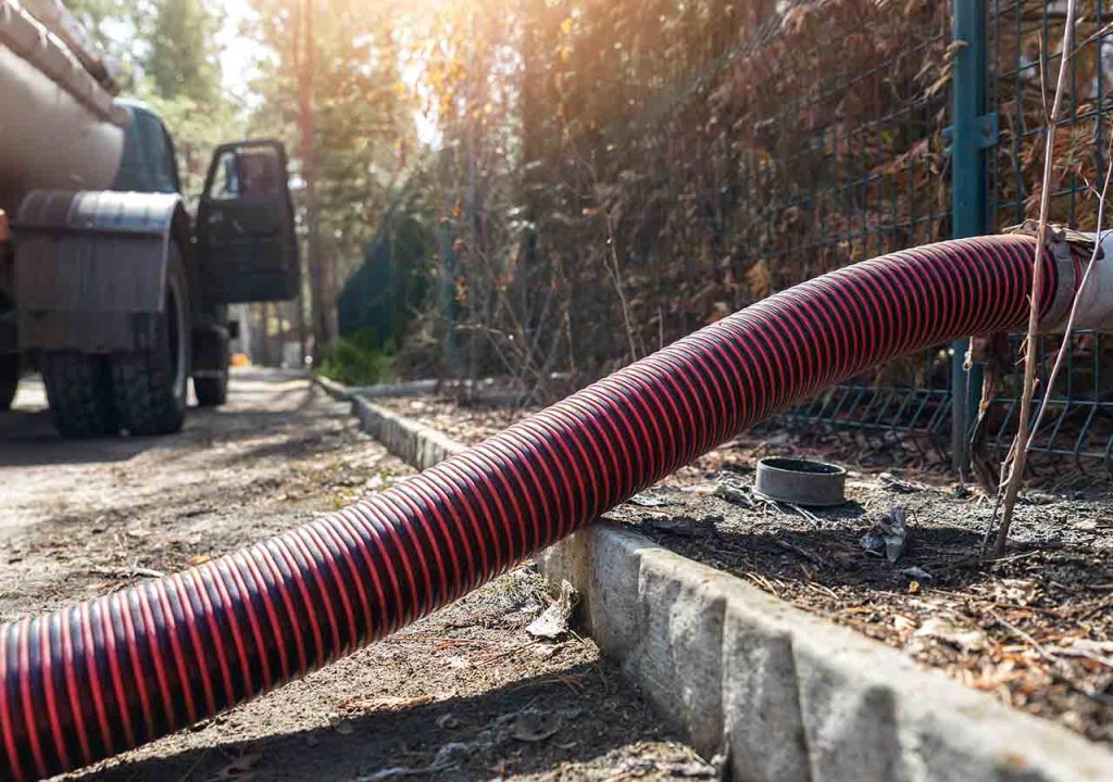 A long red pipe sucking waste from a septic tank.