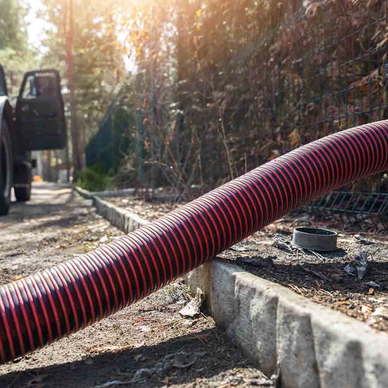 A long red pipe sucking waste from a septic tank.