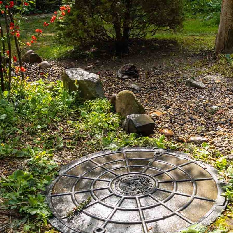 A tank lid and gravel area nearby.