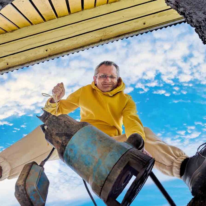 A man looking down a septic tank manhole.